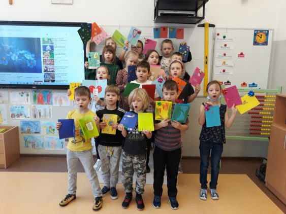 Dzieci prezentujące wykonane przez siebie laurki z okazji Dnia Babci i Dziadka.