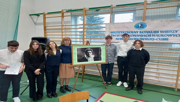 Uczestnicy konkursu z opiekunem przy zdjęciu Marii Skłodowskiej Curie